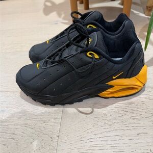 NOCTA x Nike Hot Step Air Terra sneakers in the "Black University Gold" colorway